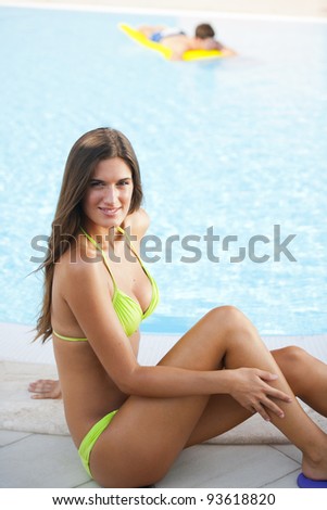 Beautiful woman sitting by pool, man on air mattress