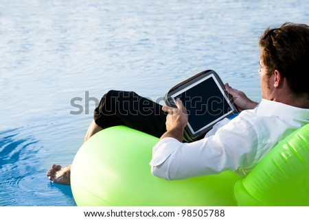 Relaxed man working with tablet PC on pool