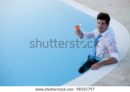 Young man having a drink in the pool, his clothes on, lots of copy-space