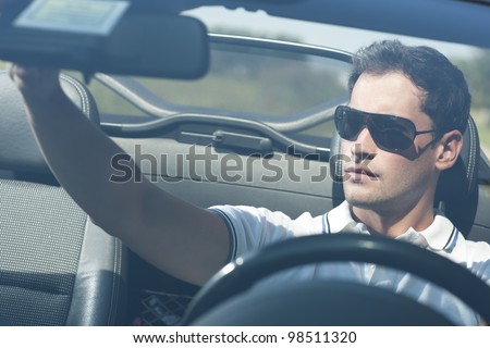Front view of a young man driving his convertible car
