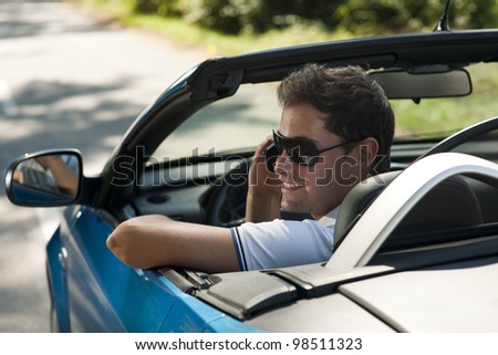 Rear view of a young man driving his convertible car