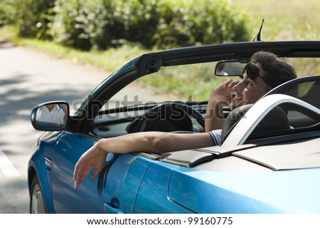 Rear view of a young man driving his convertible car