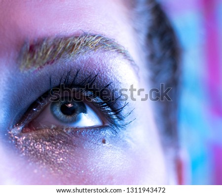 Eyes of a beautiful young woman in a bright designer makeup with rhinestones, body painting.