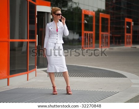Young woman in a white suit speaks over the phone