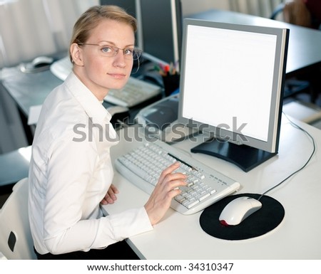 Young woman sits by computer and looks at camera