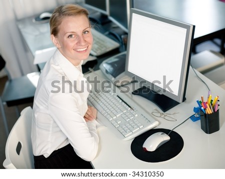 Young woman sits by computer and looks at camera