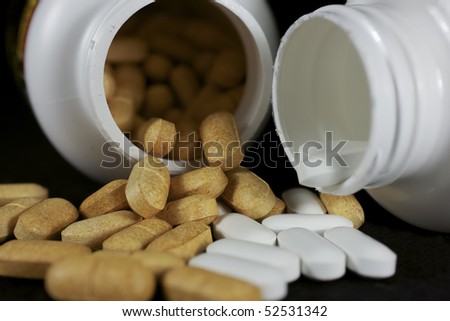 Generic pills spilling and mingling from two pill bottles.