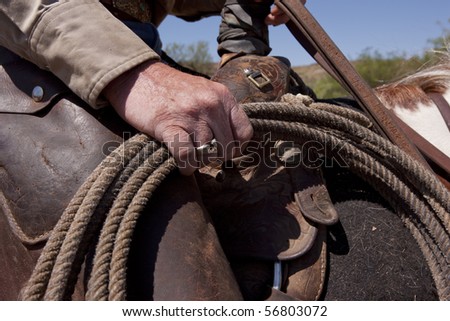 Rugged rodeo cowboy\'s hand with rope. Focus on hand.