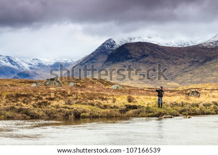 Fly fishing in a river with snow covered mountains in the back