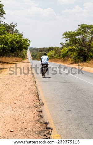 Local man riding on a bike on a desolated road in africa