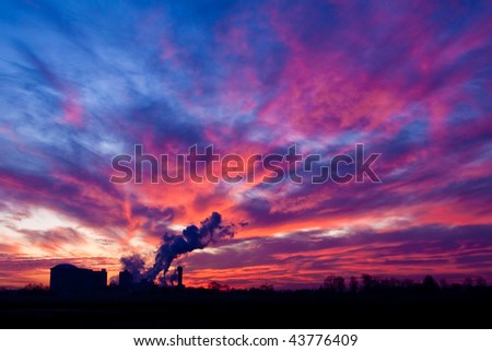 Industrial factory with smoking chimney at sunset