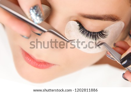 Eyelash Extension Procedure. Woman Eye with Long Eyelashes. Close up, selective focus.