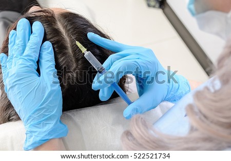 in beauty clinic cosmetician gloves making injection with a syringe in black hair roots to regenerate and give volume