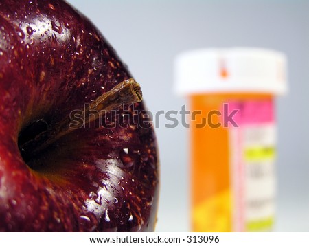 apple with water droplets in focus with prescription pill bottle faded in background signifying \