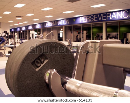 empty fitness center with freeweights in focus in foreground