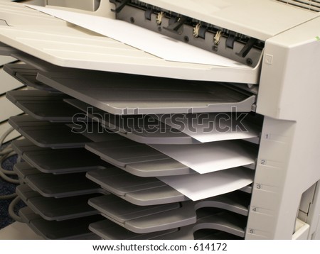a copy machine with copies in tray