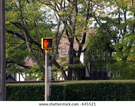 pedestrian crossing signal on a pole with out of focus trees and hedge in background
