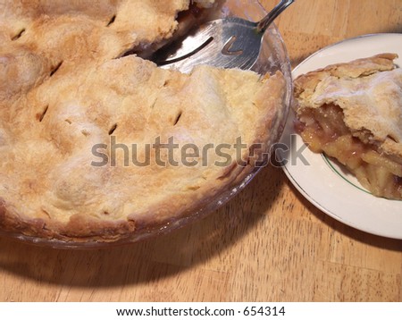 freshly baked apple pie with slice cut on a butcher block table. focus on slice of pie. shallow depth of field.