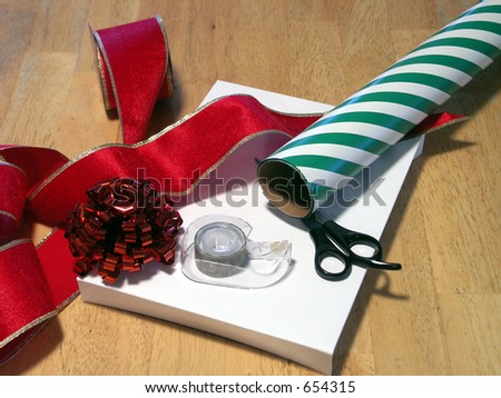 scissors, tape, ribbon and wrapping paper on a gift box. focus on tape dispenser. shallow depth of field.