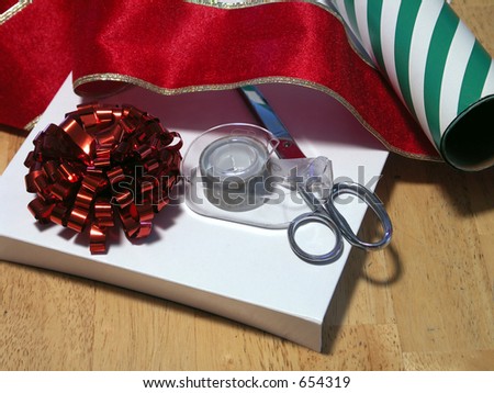 scissors, tape, ribbon and wrapping paper on a gift box. focus on tape dispenser. shallow depth of field.