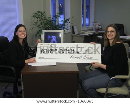 A smiling woman receives an oversized tax refund check.