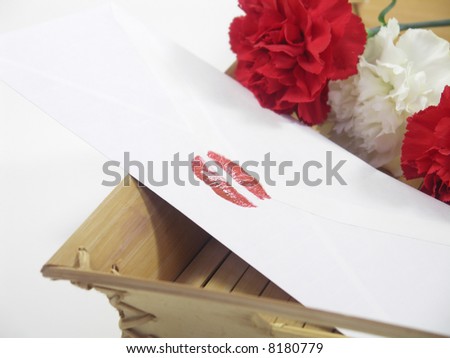 Envelope sealed with lipstick kiss and carnations in the background. Isolated on white with a shallow DOF, focus on lip print.