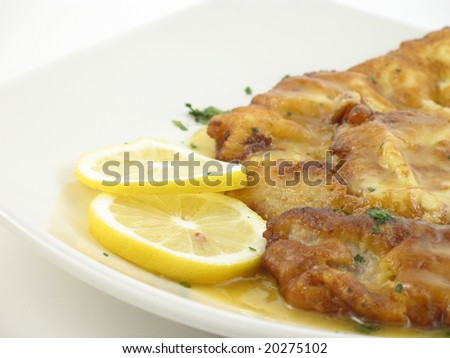 Chicken with a lemon sauce on a white plate on white background