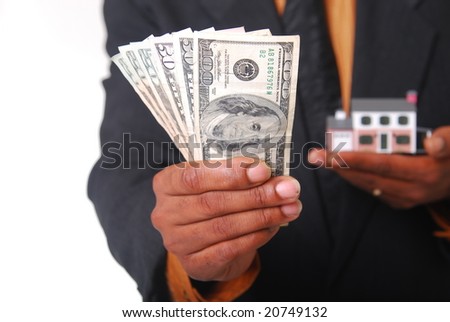 African-American male hands holding a miniature house and American currency. Shallow DOF with focus on money.