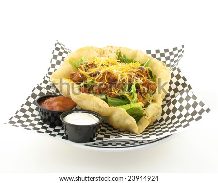 taco salad with beef in a taco shell bowl with salsa and sour cream on side