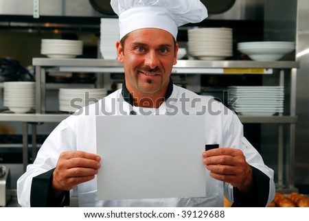 Attractive Caucasian chef holding a blank sign in a commercial kitchen