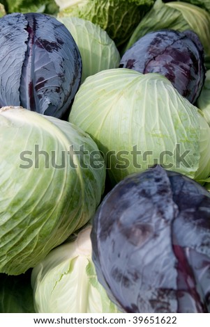 Green and purple cabbage in a pile at a farm stand