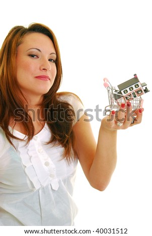 Attractive Caucasian woman holding miniature shopping cart with a house in it.