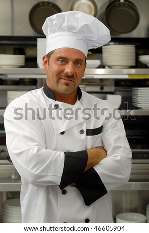 Attractive Caucasian chef standing with arms crossed in a restaurant kitchen.