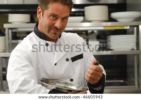 Attractive Caucasian chef mixing food in a bowl in a restaurant kitchen.