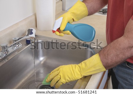 Caucasian male with dish gloves cleans the sink