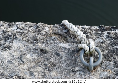 High-contrast photo of a rope tied to a ring anchored in stone