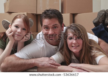 Mother, father and daughter lying on the floor in front of moving boxes.