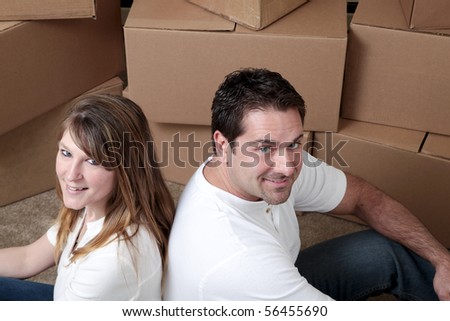 Attractive Caucasian couple sitting on the floor in front of boxes in an empty house