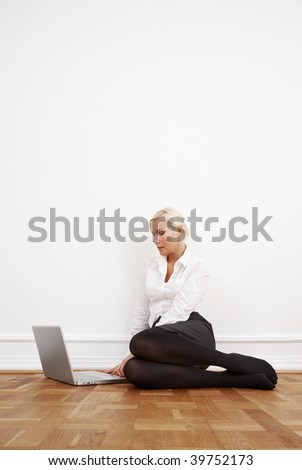 Blond businesswoman sitting on the floor with laptop