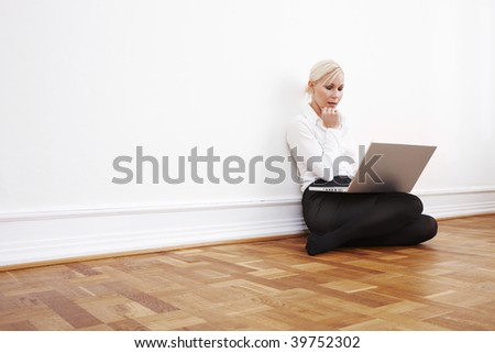 Blond businesswoman sitting on the floor with laptop