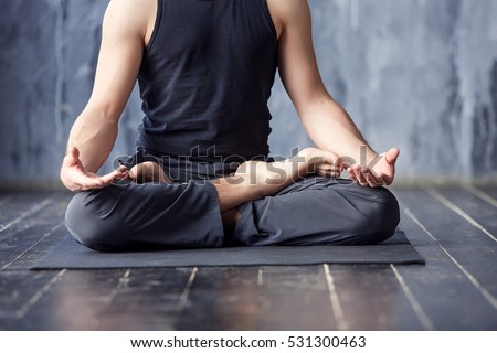 Yoga. Close up men hands. Young men do yoga indoors on black mat. Guy exercising yoga with a black background in gym. Young men meditating in lotus posture closeup.