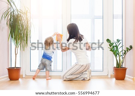 happy family doing the house cleaning. Young mother with her baby boy son washing windows together