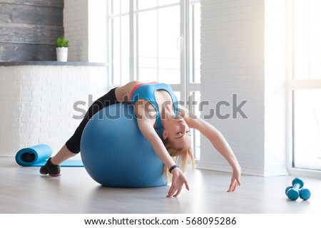 Woman in sportswear exercising her abs on a blue Pilates ball of fitball close up at home. Fitness concept