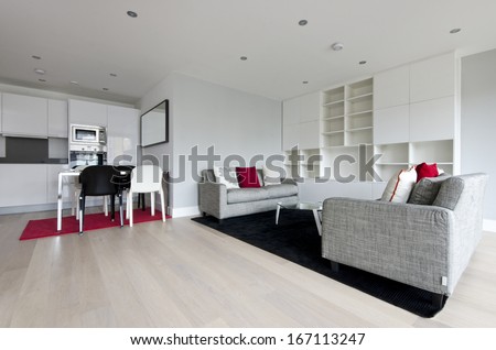 Modern Open Plan Living Area With Fully Fitted Kitchen, Dining Table For Four And Two Large Contemporary Sofas And Glass Top Coffee Table