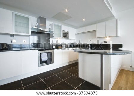 modern white kitchen with granite work top dark tiled floor and appliances