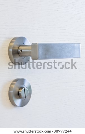 detail of a stainless steel modern door handle on a the white door