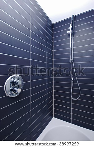 detail of a large luxury shower with shower attachment and stylish black tiles