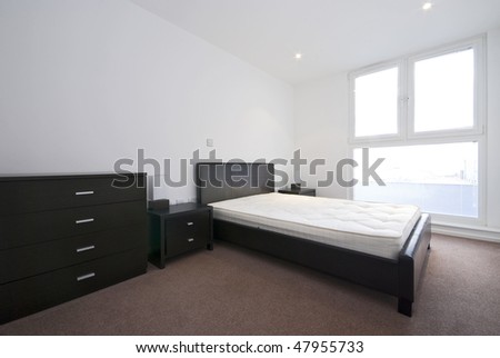 Modern double bedroom with large leather double bed and black wooden furniture