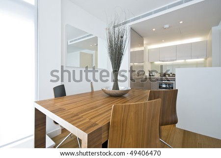 Modern dining area with wooden table, designer chairs and kitchen in a backround
