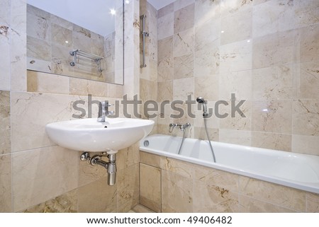 Luxurious bathroom detail with a classy bath tub, wash basin and stone tiled walls